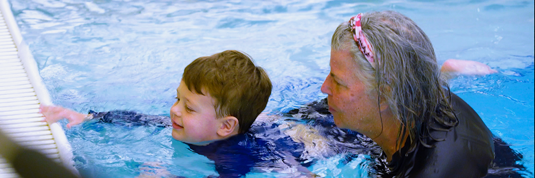 Swim lesson instructor assisting a young swimmer during swim lessons at the JCC.