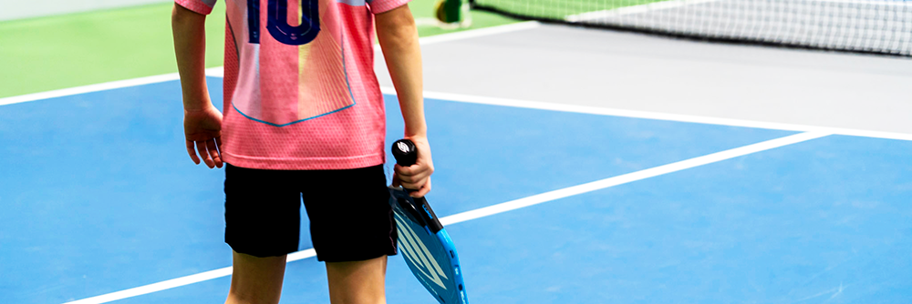 young pickleball player holding pickleball racket at a kids pickleball event at the JCC